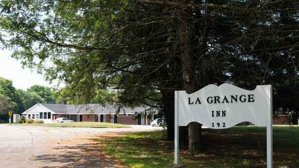 A sign for La Grange Inn, a building with a brick facade and a white roof, located at a roadside intersection. - The Lagrange Inn & Extended Stay (Pleasant Valley)