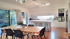Una cocina moderna con armarios blancos, una mesa de comedor de madera y un amplio ventanal.