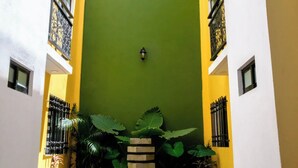 A narrow courtyard with a green door, yellow walls, and a tiled floor. - VIP 2 Bedrooms Apt at Historic Center TV Roof (Oaxaca de Juárez)