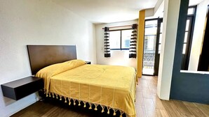 A bedroom with a bed, a nightstand, a window with curtains, and a door leading to a balcony. - VIP 2 Bedrooms Apt at Historic Center TV Roof (Oaxaca de Juárez)