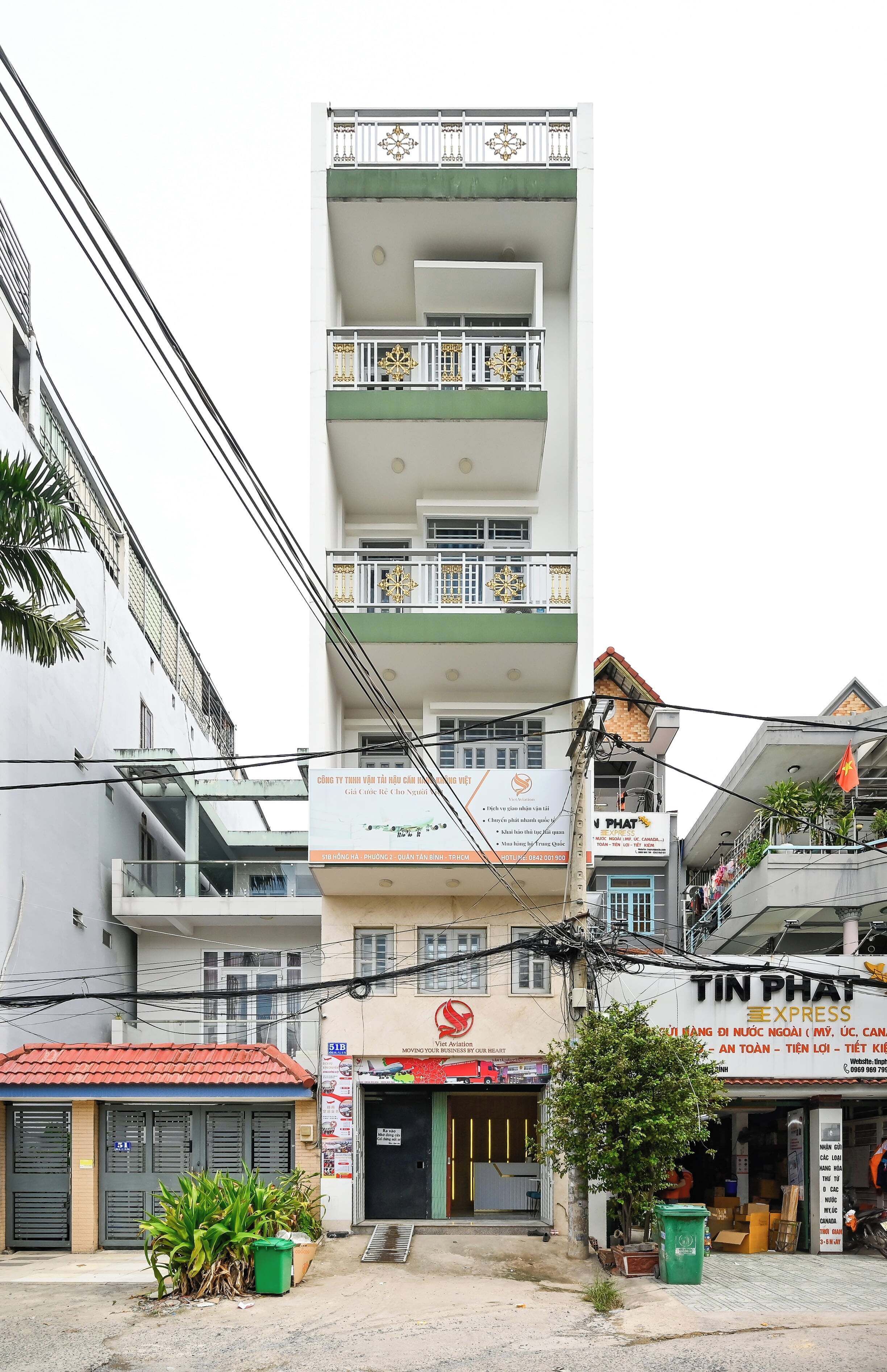A multi-story building with a commercial ground floor, including a shop with a red awning and a sign for 'TIN PHAT EXPRESS'.