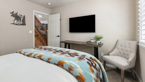 Un dormitorio con una cama, una silla, un televisor y una escalera.