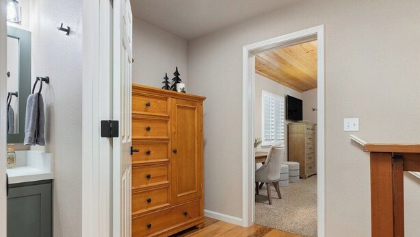Un pasillo con un aparador de madera, un espejo y una puerta que da a otra habitación.