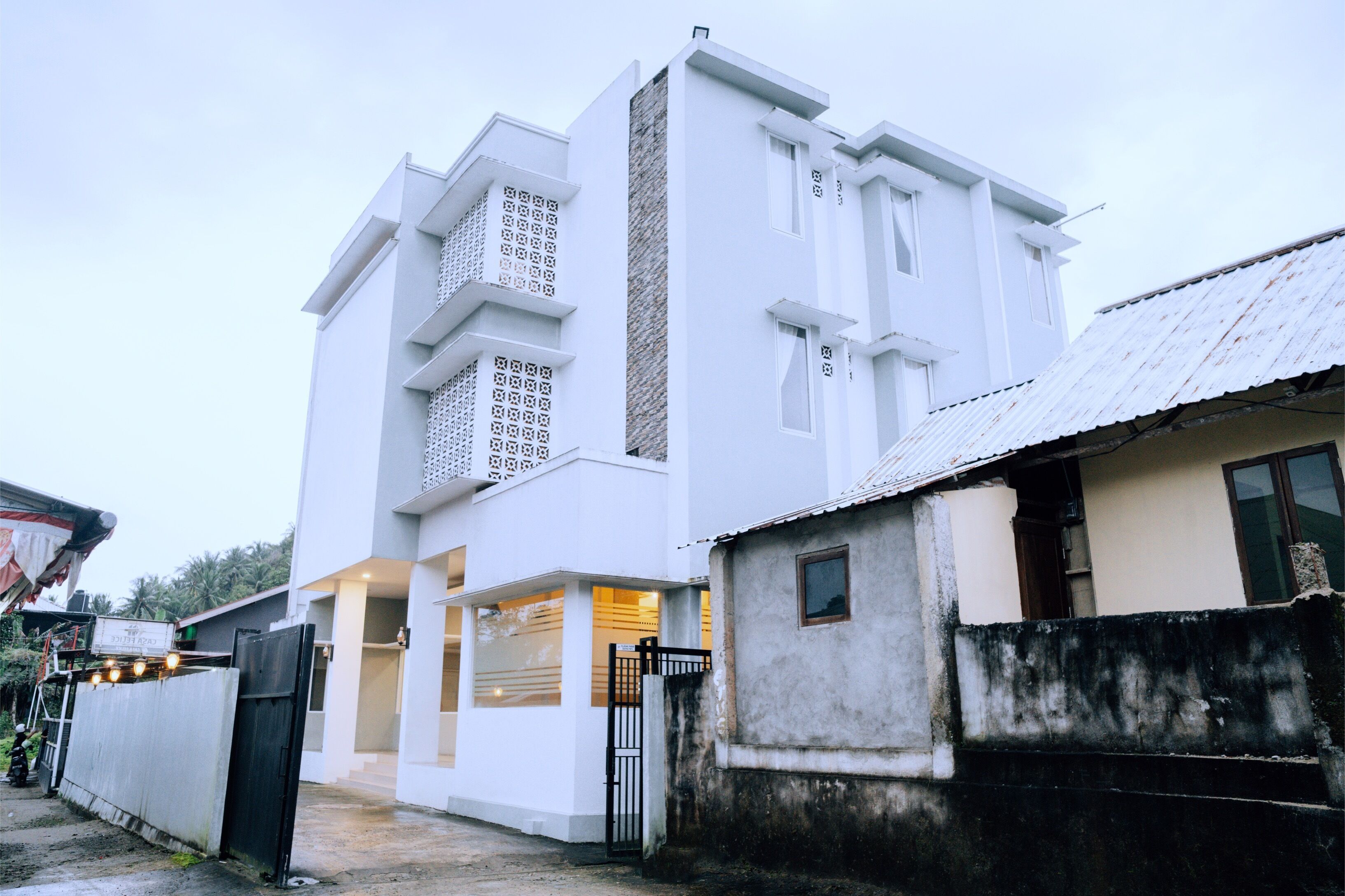 Un edificio moderno blanco con una entrada amplia y una estructura pequeña adyacente.