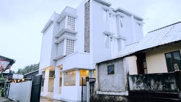 Un edificio moderno blanco con una entrada amplia y una estructura pequeña adyacente.
