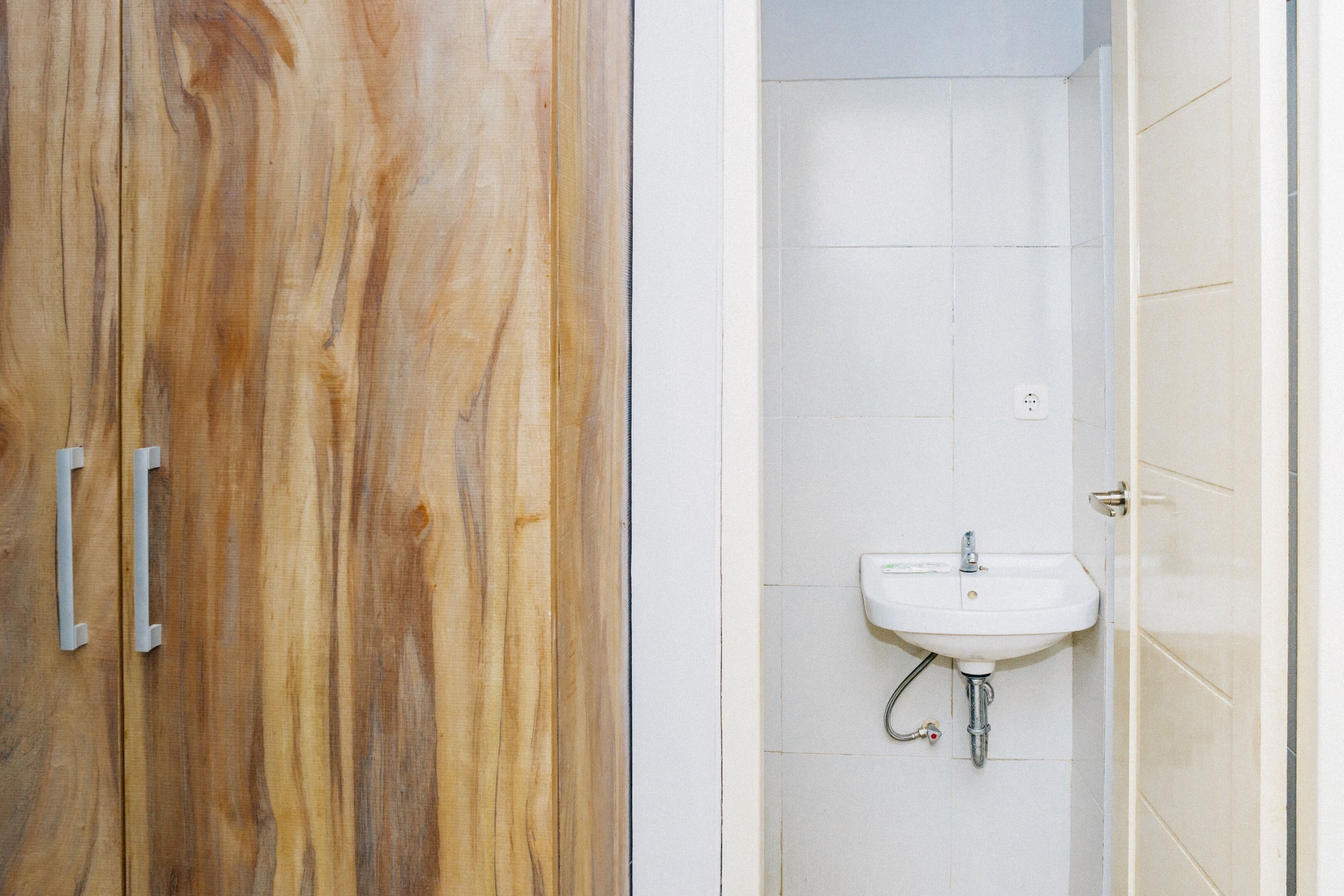 Un baño con tocador de madera y lavamanos blanco.
