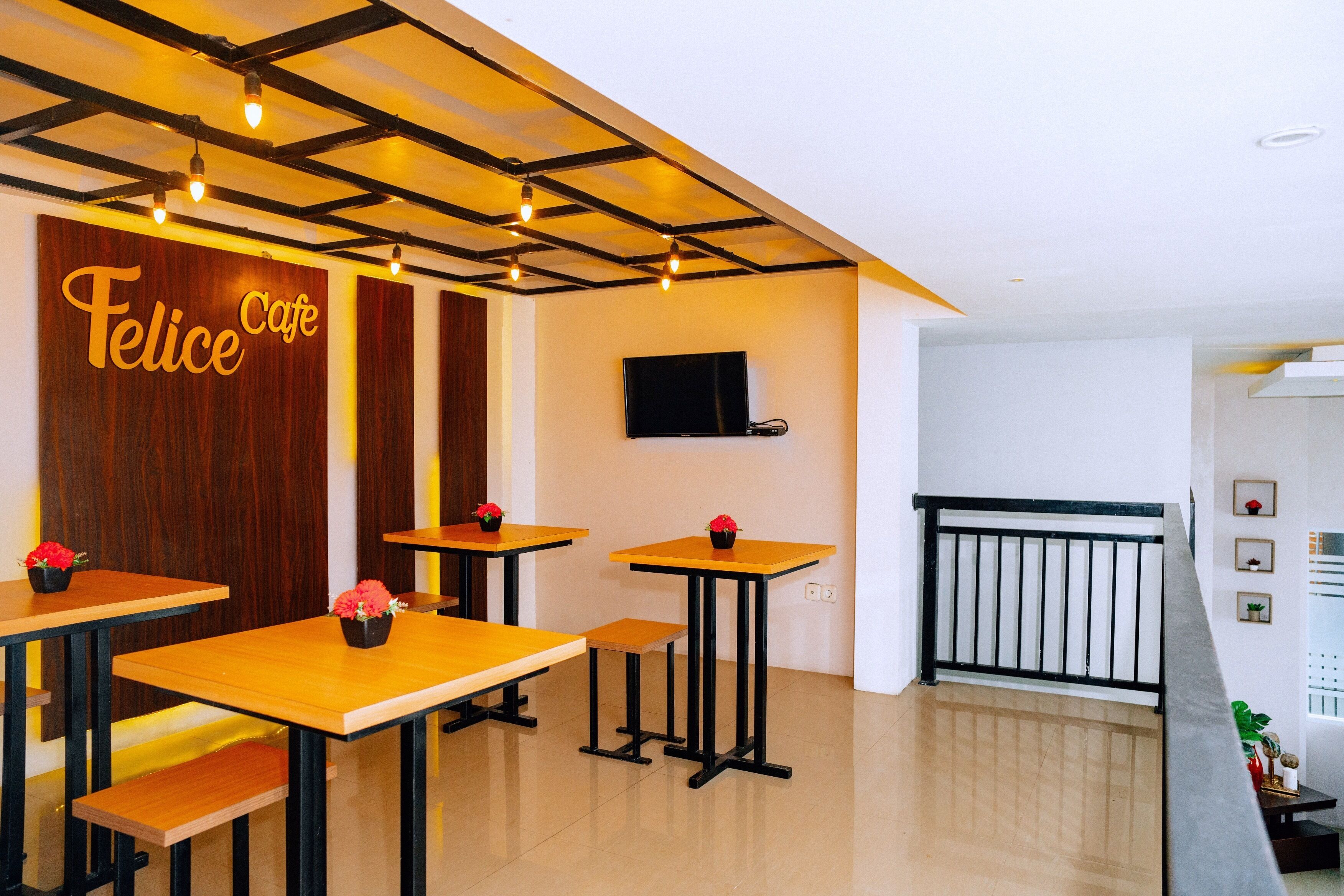 Ein Café-Interieur mit Holztischen, schwarzen Metallgestellen und roten Blumen.