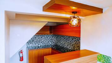 Una cocina moderna con armarios de madera, un protector contra salpicaduras a cuadros y una lámpara colgante de diseño geométrico.