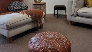 Un salón con sofá, reposapiés, lámpara de pie y aire acondicionado instalado en la pared.