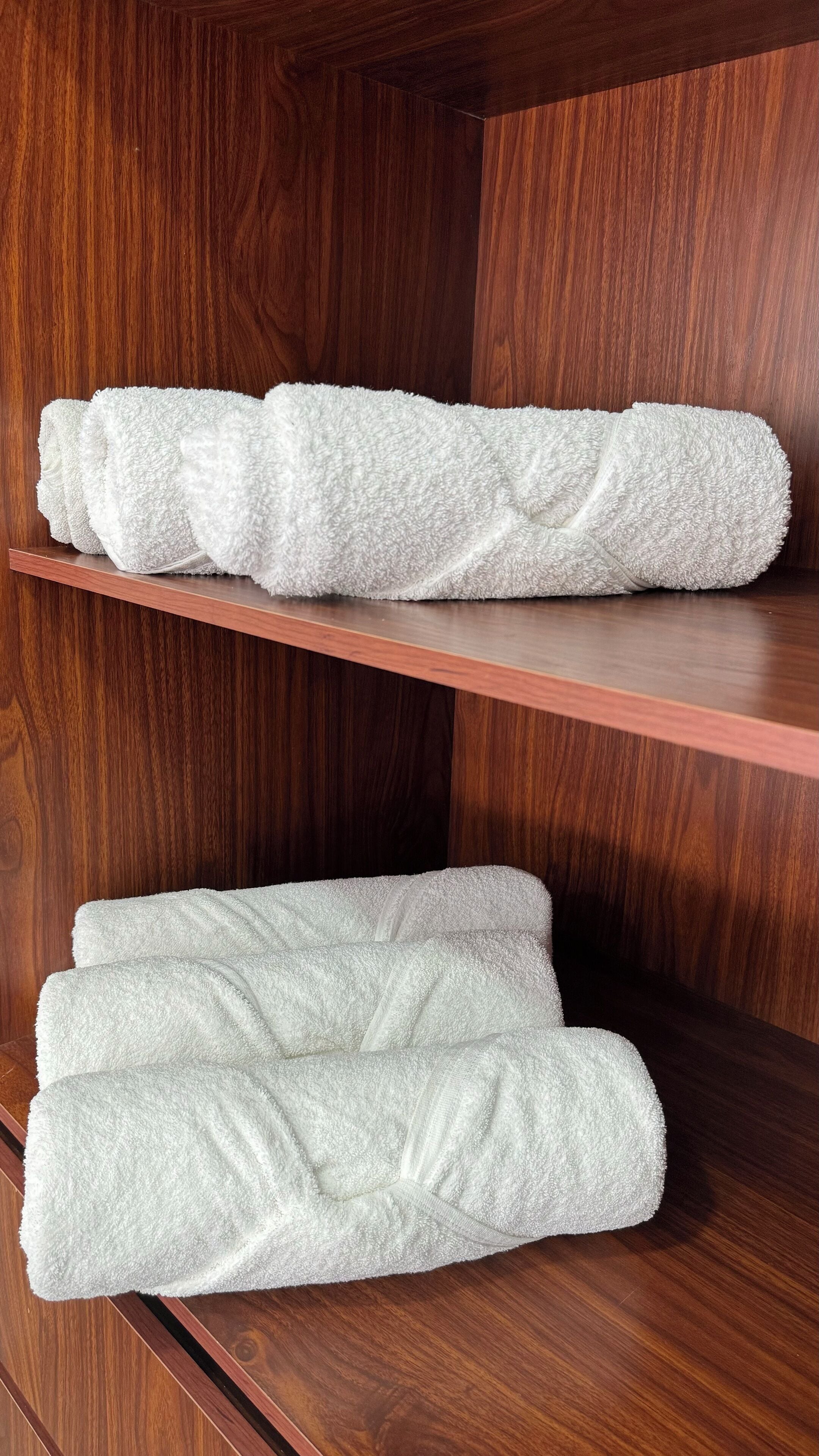A wooden shelf with folded white towels.