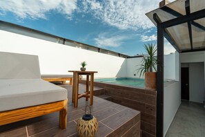 An outdoor seating area with a pool, wooden furniture, and potted plants. - Nabani condominios T2 (Santa María Huatulco)