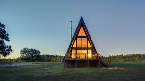 Uma cabana moderna em estilo A com um amplo deck e uma escadaria que leva à entrada.