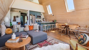 Um espaço de estar estilo loft com cozinha, área de refeições e um canto aconchegante com sofá e cadeiras.