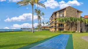 A hotel with a pool, palm trees, and a view of the ocean. - Rare LUX Oceanfront Views, Pool, Paradise - Papakea L402 (Lahaina)