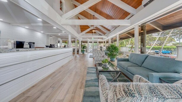 A spacious indoor area with a wooden ceiling, a long counter with a television, and seating arrangements. - Rare LUX Oceanfront Views, Pool, Paradise - Papakea L402 (Lahaina)