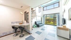 A modern kitchen with a dining area, a sofa, and a balcony with a view. - Gapyeong Beilli pet Pool Villa Pension (Gapyeong)