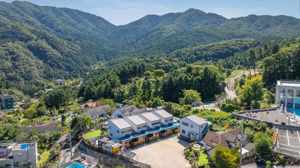 Un quartier résidentiel avec des maisons modernes, une piscine et une vue sur des montagnes boisées.