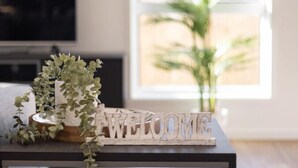 Een donkerhouten consoleschrank met een 'WELCOME' bord, een kleine potplant en een lijst met een foto.