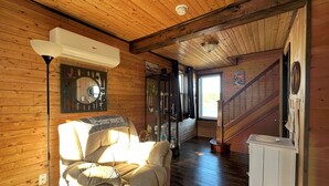 Una habitación acogedora con piso de madera, un sofá, un ventilador de techo y una escalera que sube a otro nivel.