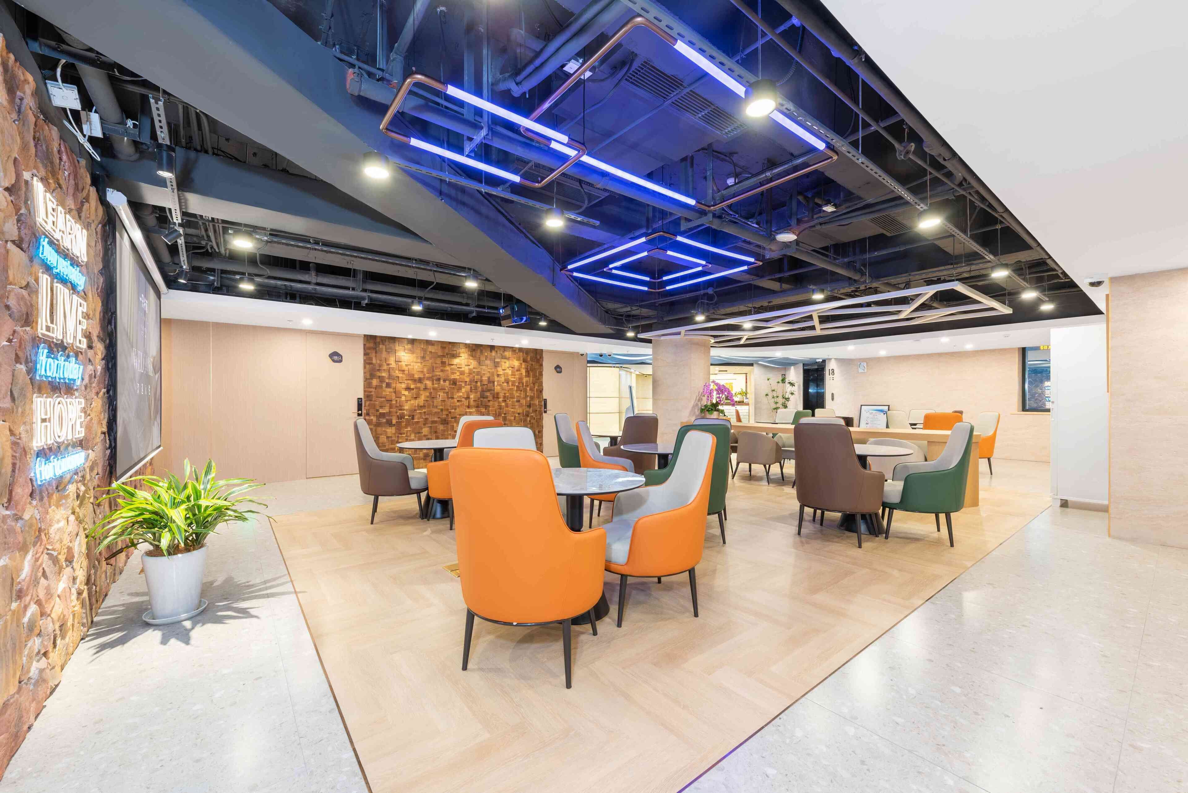 A modern indoor space with a brick wall, a potted plant, and a variety of seating arrangements including tables and chairs.