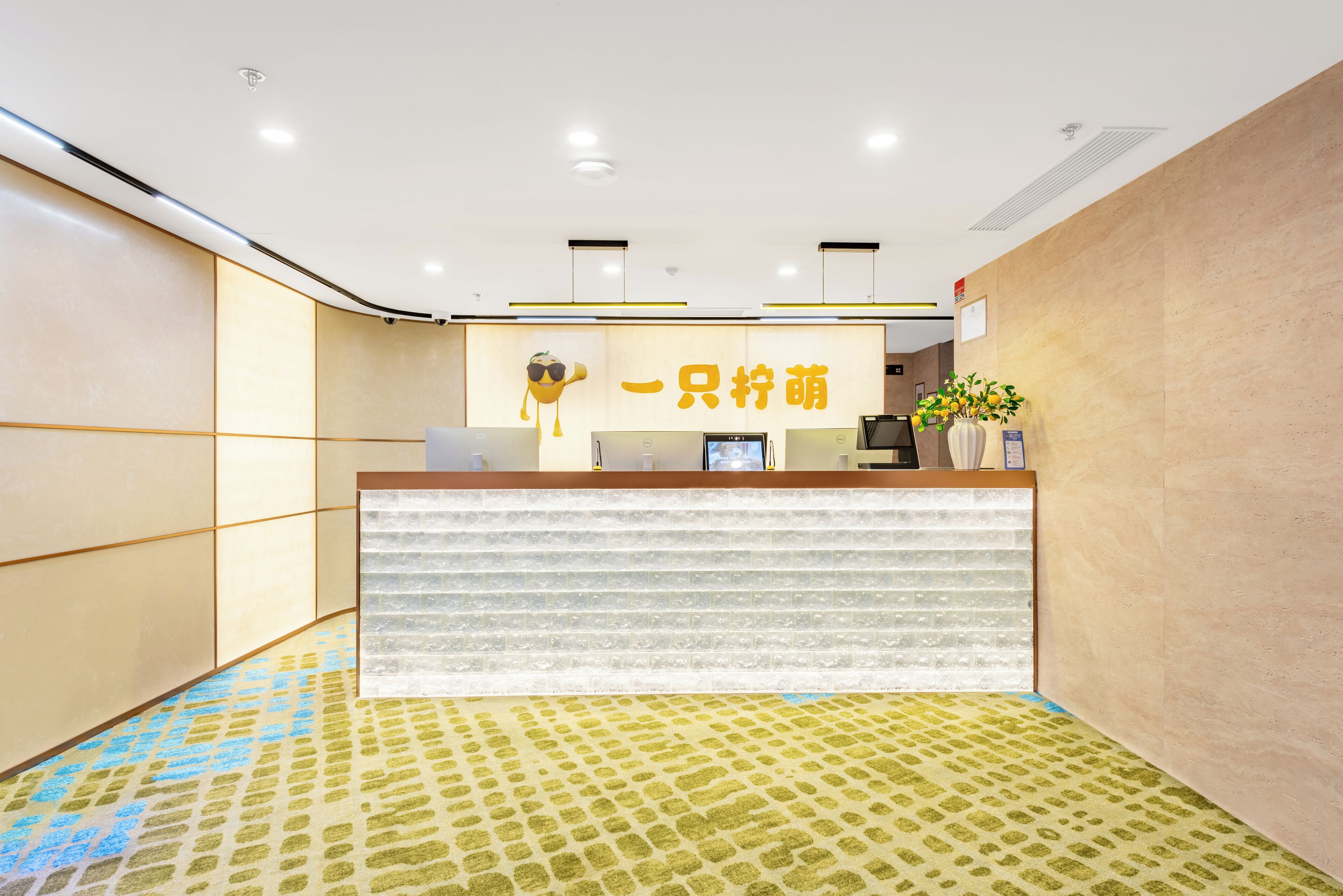 A reception desk with a modern design, a logo above it, and a potted plant on the right.