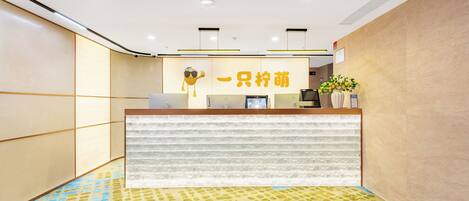 A reception desk with a modern design, a logo above it, and a potted plant on the right.
