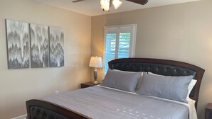A bedroom with a large bed, a nightstand with a lamp, and three wall-mounted paintings. - Home with a large yard-Minutes from Downtown!!! (Beaufort)