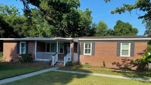 A two-story brick house with a front porch, a small front yard, and a sidewalk leading to the entrance. - Home with a large yard-Minutes from Downtown!!! (Beaufort)