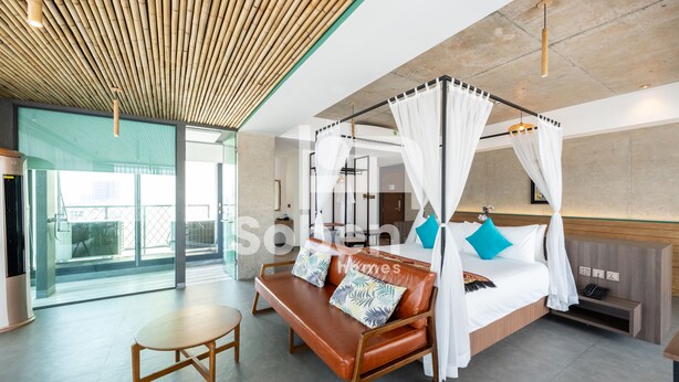 A modern hotel room with a four-poster bed, a wooden bench, and a small table. - Royal Palace Suites Phnom Penh by Soben (Phnom Penh)