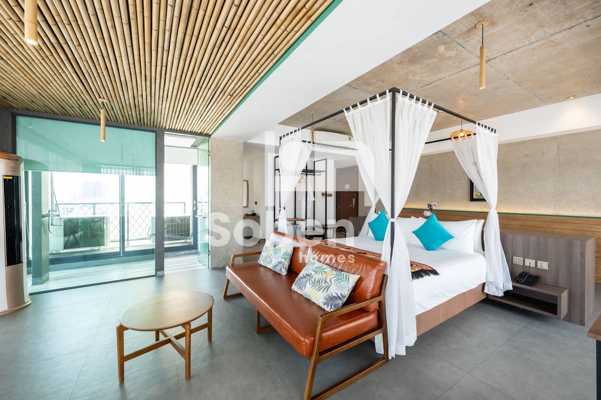 A modern hotel room with a four-poster bed, a wooden bench, and a small table.