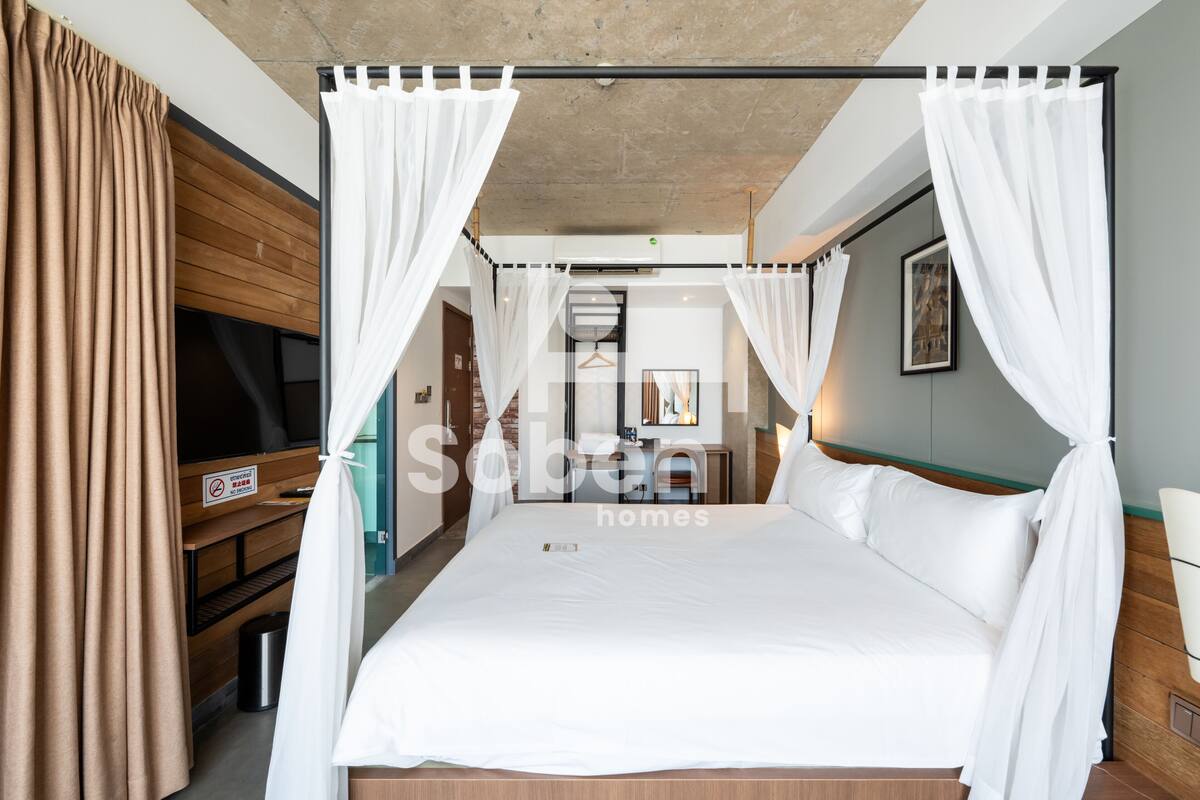 A hotel room with a bed, a TV, and a wooden bench.