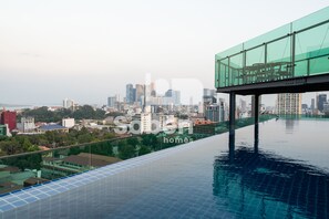 Una piscina infinita en la azotea con vista a la ciudad, barandillas de vidrio y un diseño arquitectónico moderno.