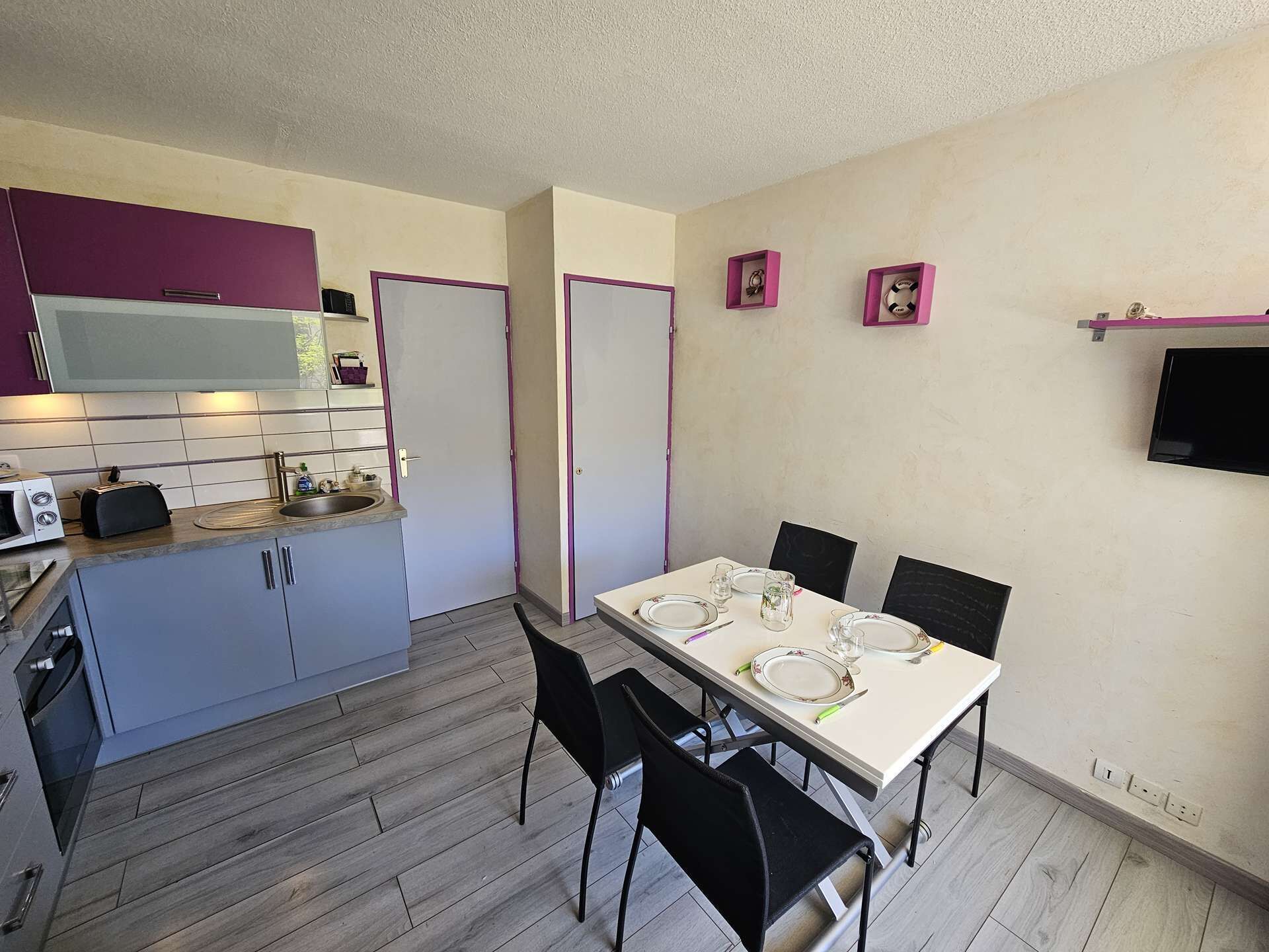 Une cuisine compacte avec un coin repas, comprenant une table pour quatre personnes, un four à micro-ondes et un grille-pain.
