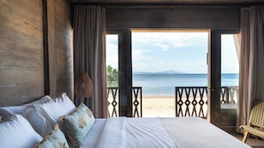 Ein Schlafzimmer mit einem großen Bett, Meerblick und einem Balkon mit einem Stuhl.