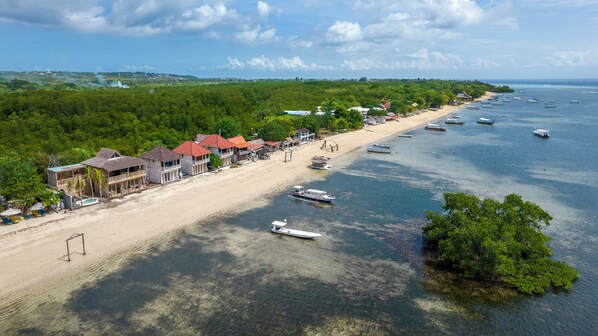 Um resort costeiro com villas na praia, águas cristalinas e barcos.