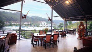 A spacious dining area with a large table and chairs, a chandelier, and a view of the surrounding landscape.