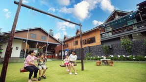 A wooden swing set in a backyard with a house in the background.