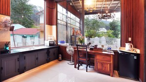 A kitchen with a large window, wooden cabinets, a refrigerator, and a dining area with a table and chairs.