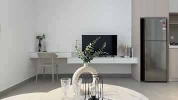 A modern kitchen with a built-in refrigerator, a dining area with a round table, and a TV mounted on the wall.