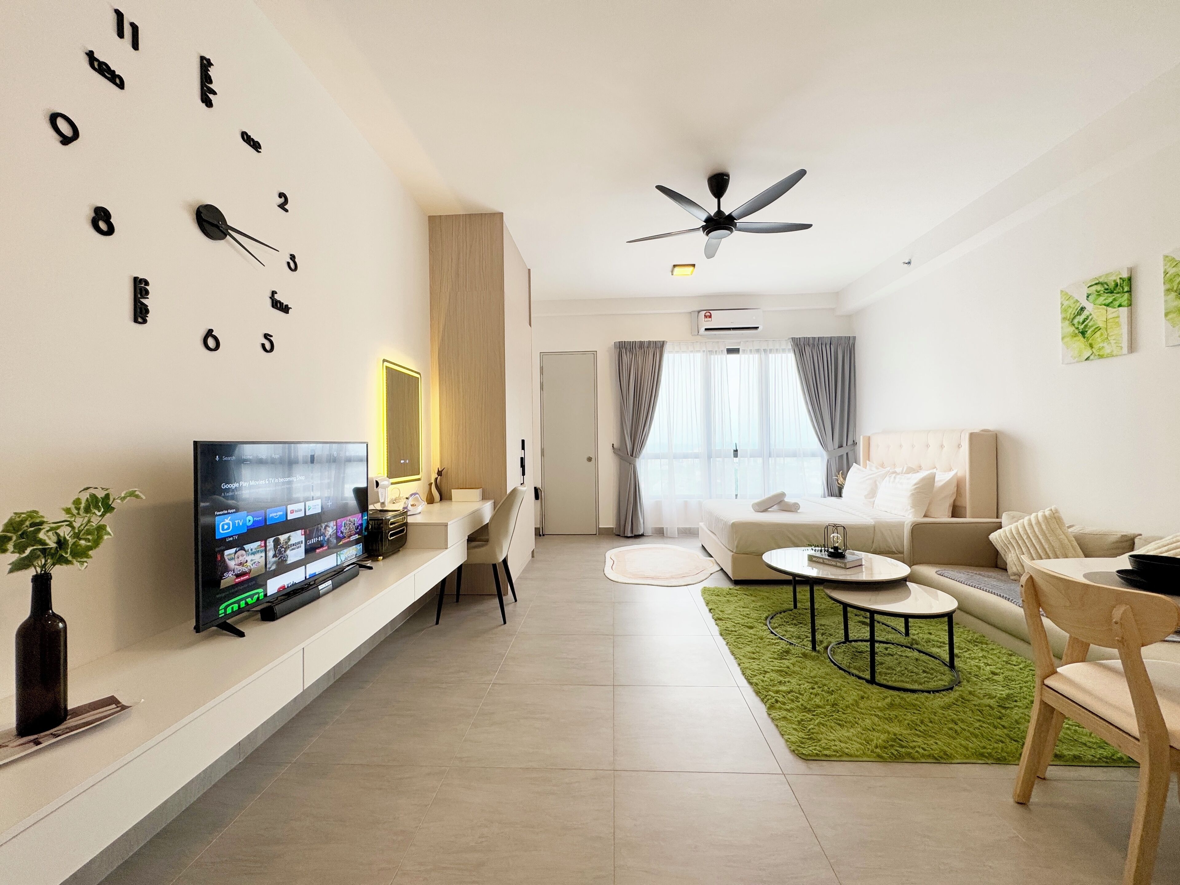 A modern living room with a flat-screen TV, a ceiling fan, and a large clock on the wall.