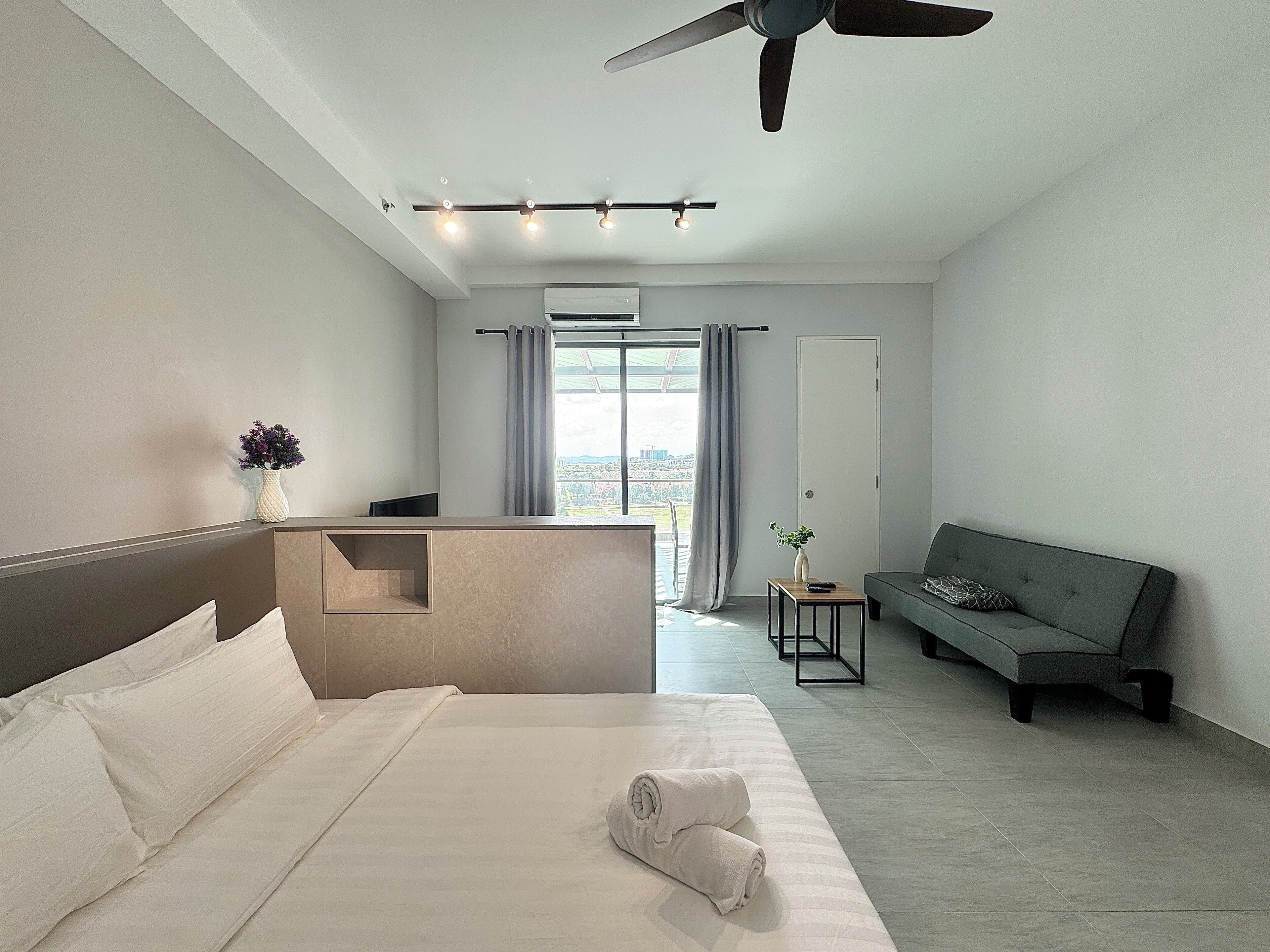 Une chambre d’hôtel moderne avec un grand lit, un canapé, une petite table et un ventilateur de plafond.
