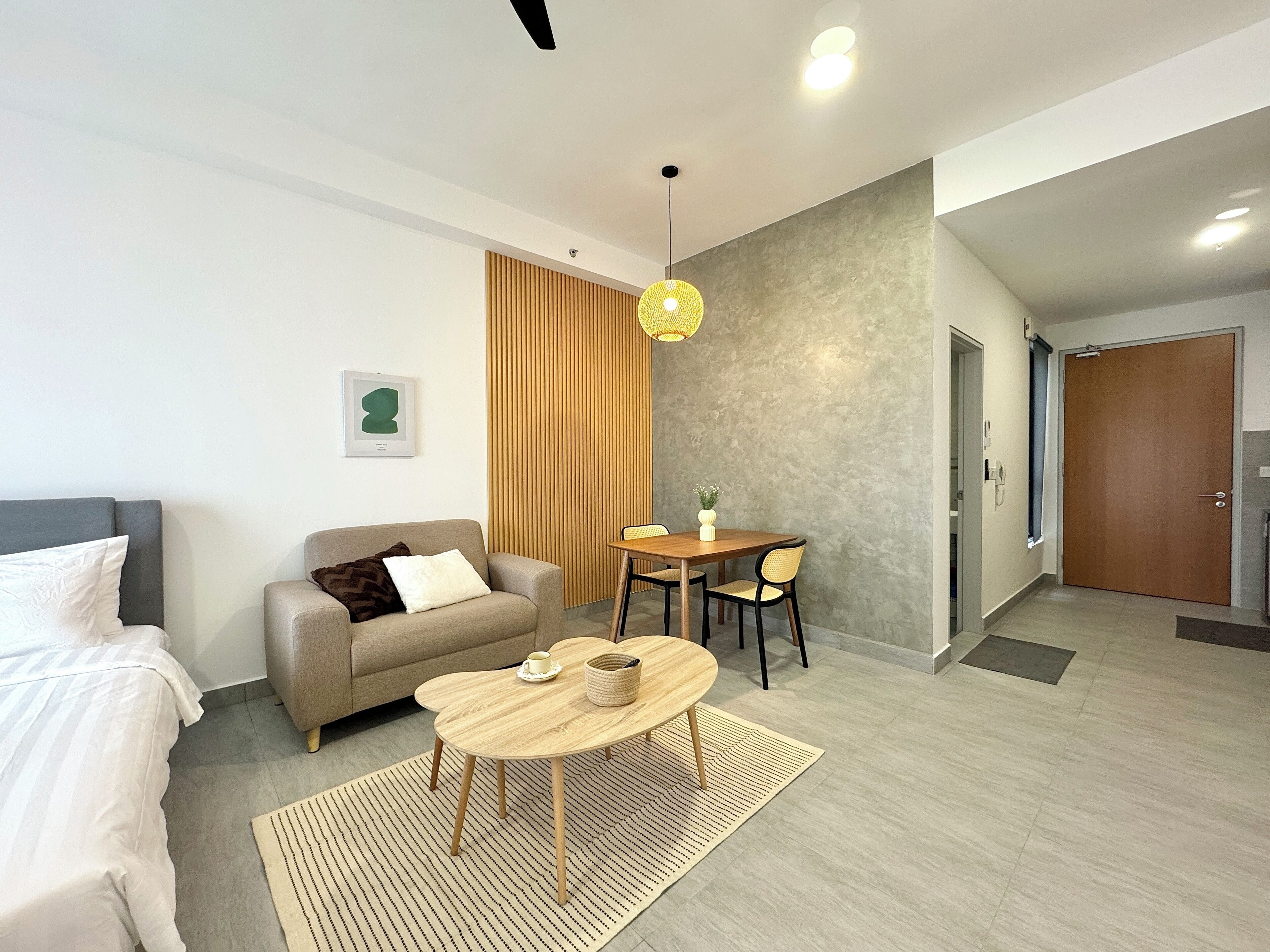 Moderni hotellihuone, jossa on sohva, pieni ruokapöytä ja kattotuuletin.