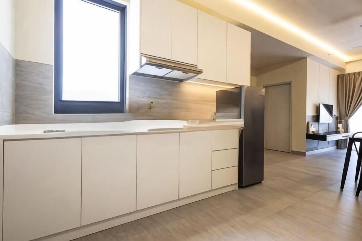 Una cocina moderna con una isla grande, electrodomésticos integrados y un ventanal que proporciona luz natural.