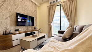 Une chambre d’hôtel moderne avec un mur en marbre, un téléviseur à écran plat diffusant des services de streaming, un canapé et un lit agrémenté d’un couvre-lit à motifs.