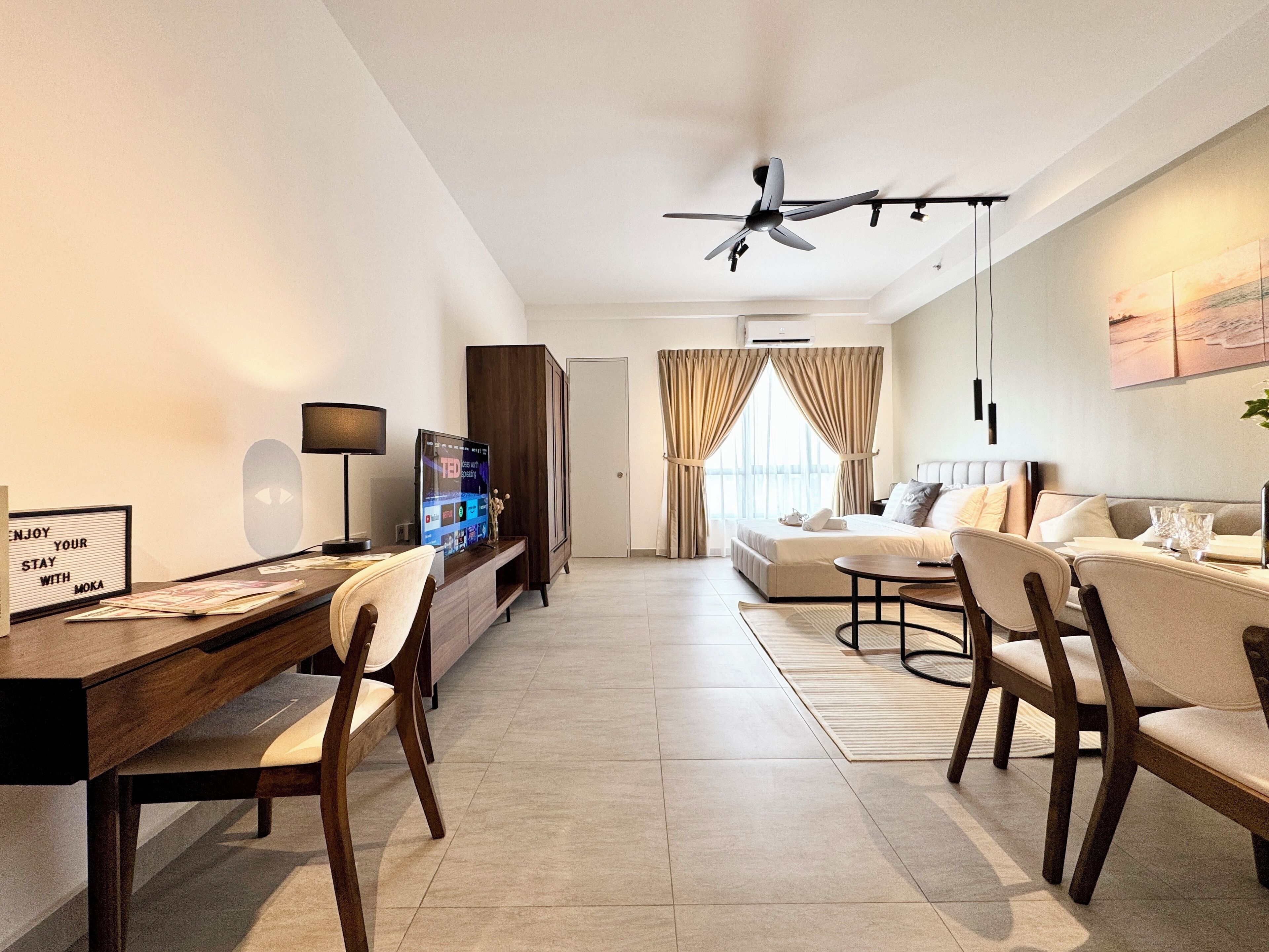 A modern hotel room with a dining area, a TV, a desk, and a bed.