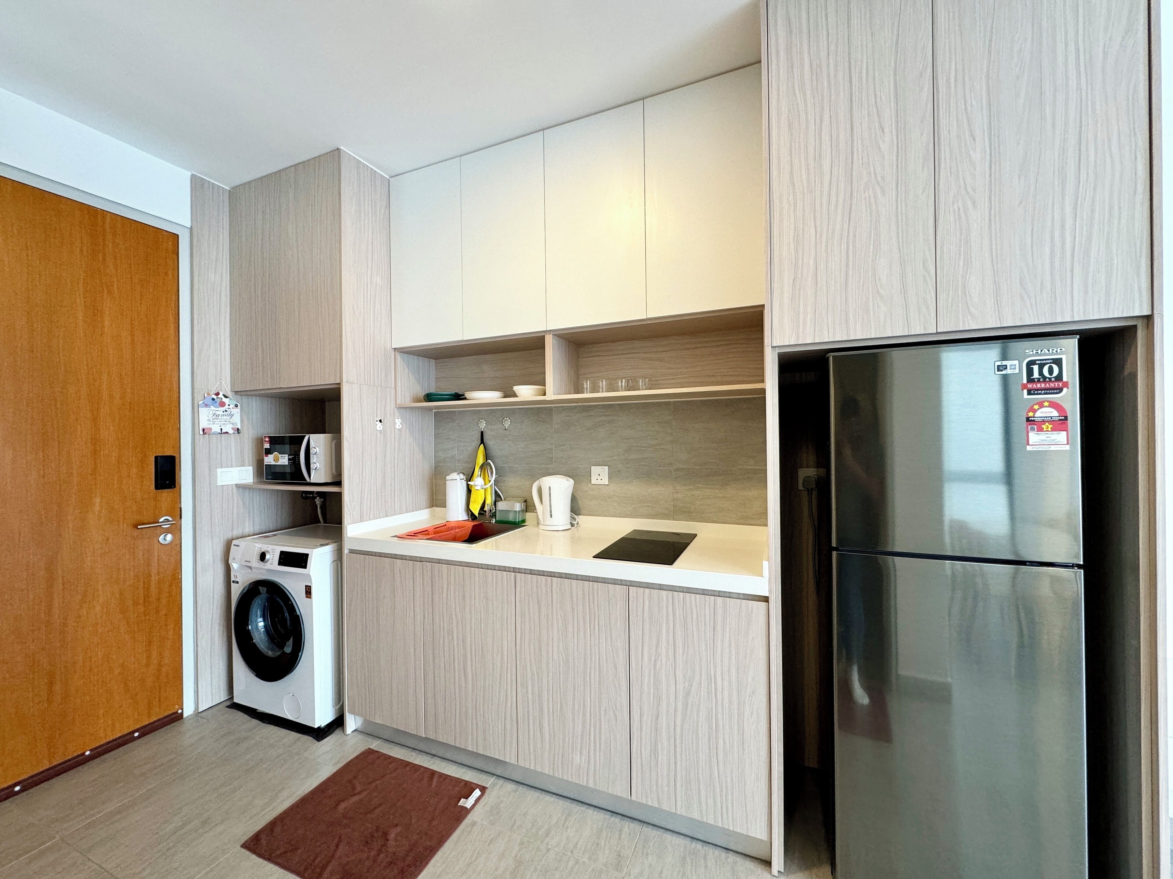 A modern kitchen with a stainless steel refrigerator, a washing machine, and a microwave.
