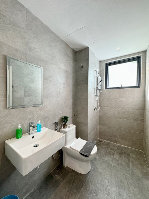 A modern bathroom with a large mirror, a sink, a toilet, and a shower.