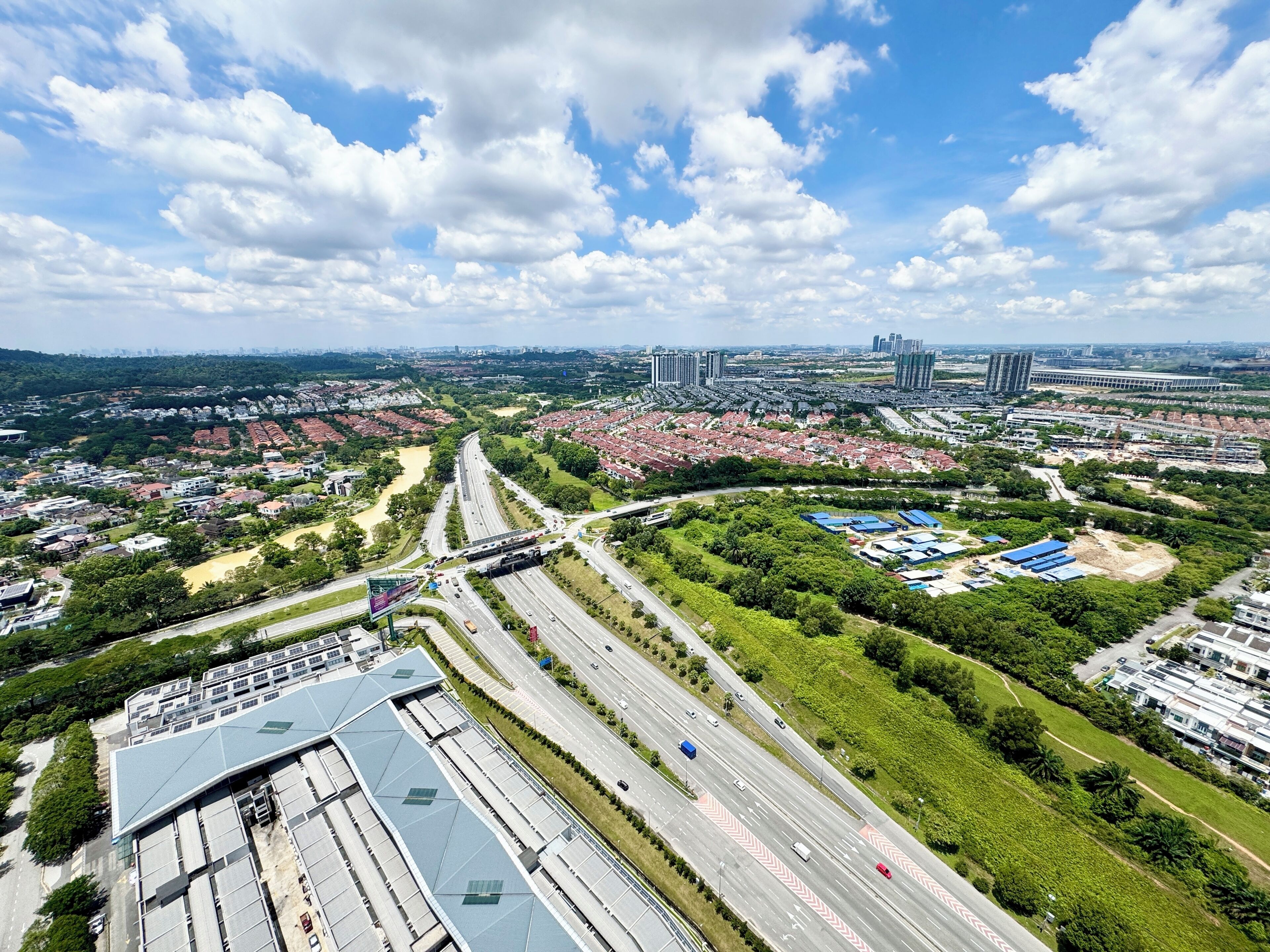En vy över en stad sedd från luften, med en motorväg, bostadsområden och moderna byggnader.