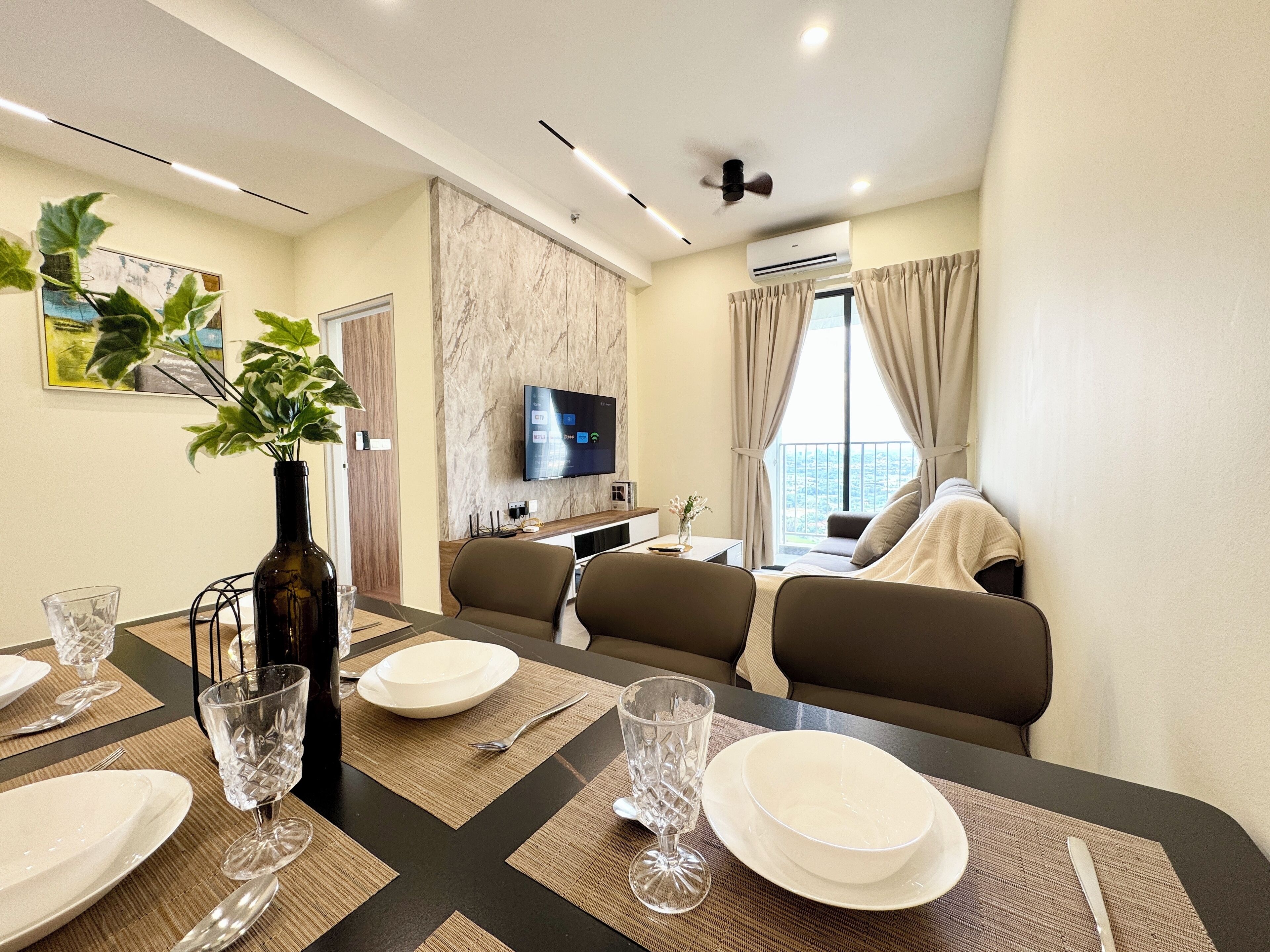 Une chambre d’hôtel moderne dotée d’un coin repas, d’un téléviseur à écran plat et d’une grande fenêtre avec des rideaux.