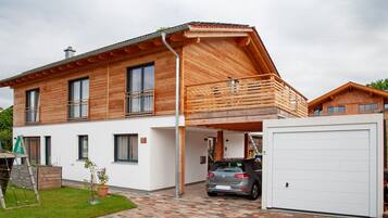 Une maison à deux étages avec un garage, une véranda et un petit jardin.
